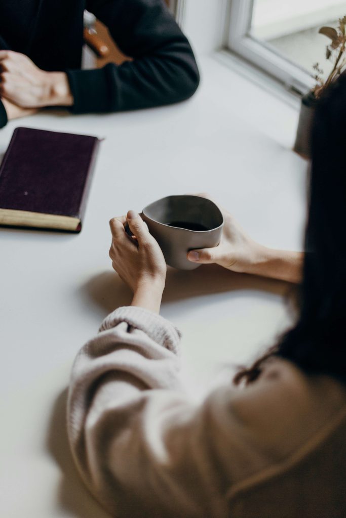 Two people sitting at a table with coffee, having a warm and supportive conversation — symbolizing therapist collaboration.